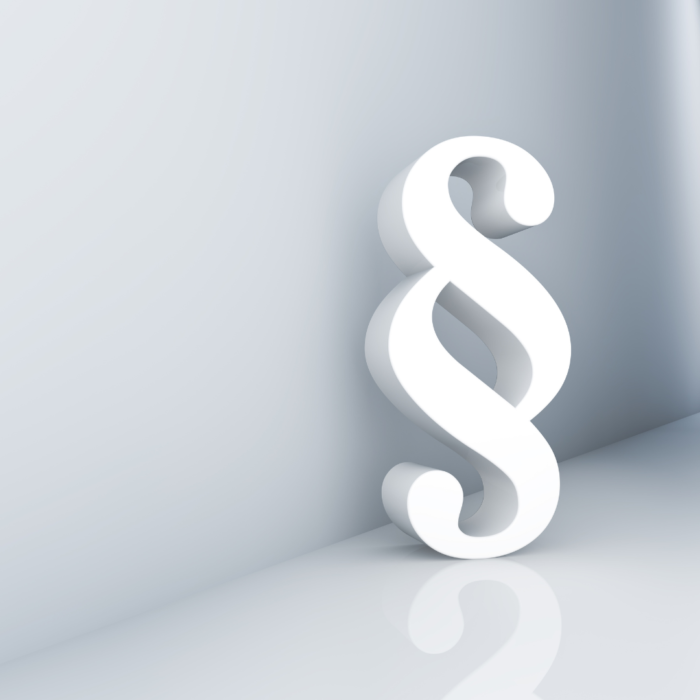 A stock image of a white symbol of paragraph leaning against the white wall.