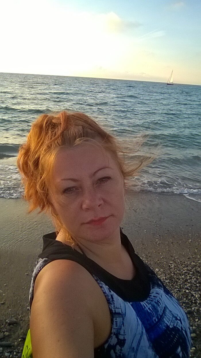 a slefie of a redhair woman with the see in the background