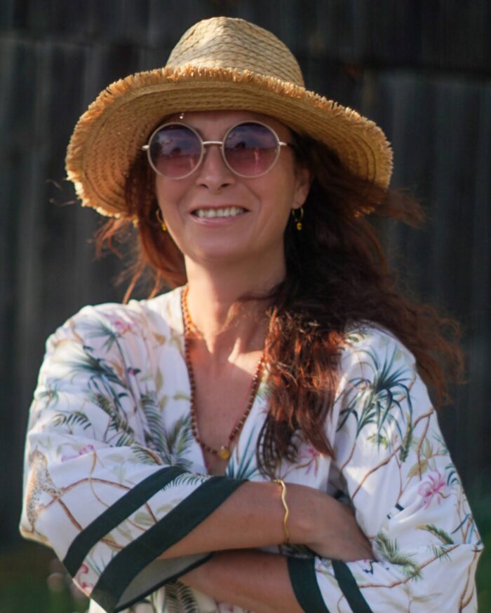 A photo of Anna Szaniawska - smiling, in a sun hat and sunglasses